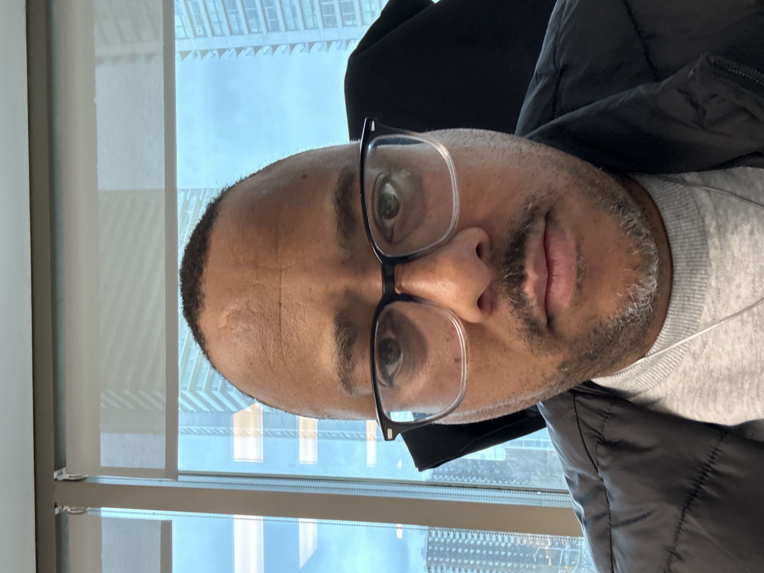 Clinton Reid, Account Director, selfie in office building with city skyline window behind