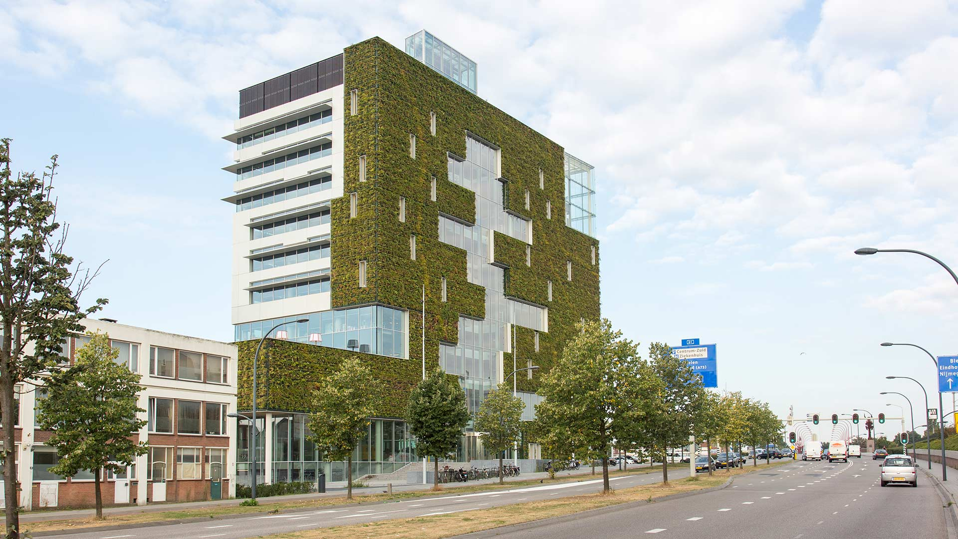 Modern urban building with a green living wall facade, city street in foreground