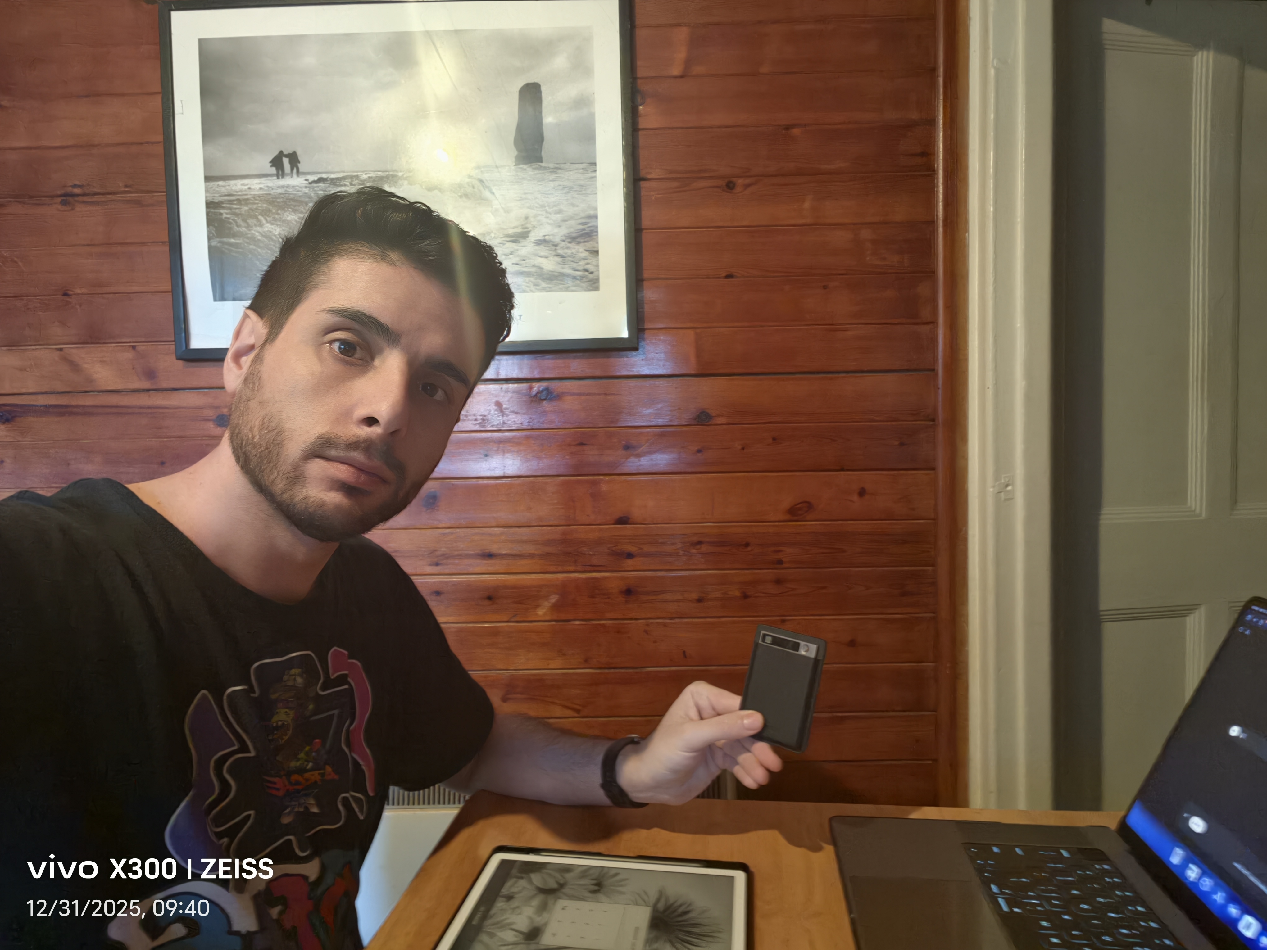 Salvatore Santillo at a table holding a small device, laptop and tablet visible on desk